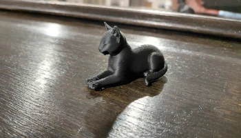 Современная фигурка лежащего черного кота...